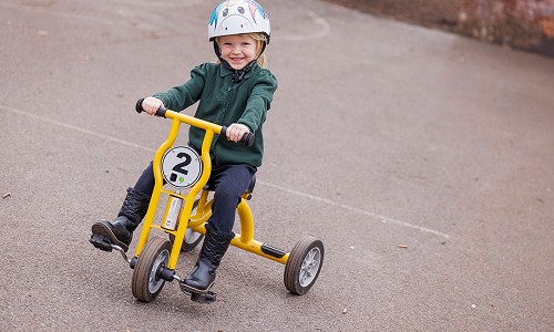 Disgybl Ysgol Gymraeg Trefynwy yn gwennu ar beic